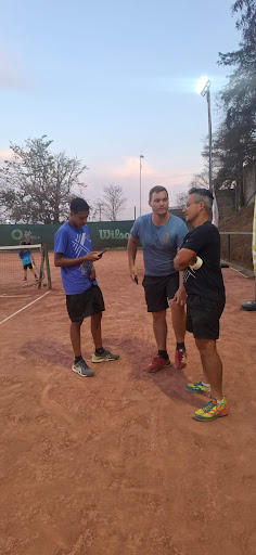 Professor de tênis em quadra explicando uma atividade